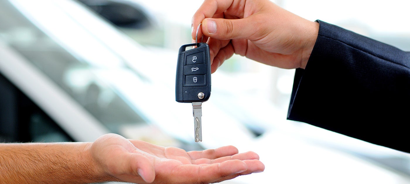 Car salesman passing key to customer